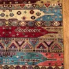 Detailed corner view of an Afghan Uzbek wool rug showing horizontal geometric bands, triangle amulet stripes, and fringe over a wood floor.