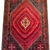 Full overhead view of a 5' 9" x 7' 5" hand-knotted Persian Shiraz wool rug featuring a large stepped red diamond medallion with dense concentric filler patterns, dark navy spandrels, and geometric borders.