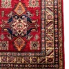 Detailed corner view of an Afghan Kazak wool runner rug showing an ivory geometric border, navy tribal medallion, and clean white fringe