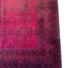 Detailed corner view of an Afghan Torkman wool rug showing dark multi-tiered border bands, crenellated arch guard lines, and flat-woven fringe edge.