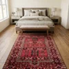 Hand-knotted Afghan Torkman wool rug extending beneath an upholstered bed and neutral bench in a warm, minimalist bedroom suite.