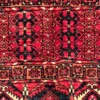 Close-up of horizontal geometric stripes, square meanders, and plush wool pile on a crimson Afghan Torkman rug