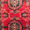 Close-up of the circular sunburst medallion, stylized bird motifs, and plush hand-spun wool pile on a red Afghan Uzbek rug.