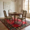 Afghan Uzbek wool area rug styled beneath a round wood dining table and four upholstered chairs under a classic chandelier.
