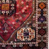 Detailed corner view of a Persian Shiraz wool rug showing the dark geometric spandrel, serrated border stripe, and white fringe edge.