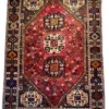 Full overhead view of a 5' 5" x 7' 8" hand-knotted Persian Shiraz wool rug featuring a large hexagonal red field with three stacked tribal medallions and dark espresso geometric spandrels.