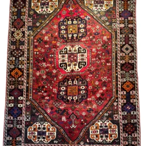 Full overhead view of a 5' 5" x 7' 8" hand-knotted Persian Shiraz wool rug featuring a large hexagonal red field with three stacked tribal medallions and dark espresso geometric spandrels.