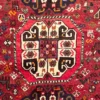Close-up of the central ivory and terracotta tribal medallion, zoomorphic animal figures, and lustrous wool pile on a red Persian Shiraz rug.
