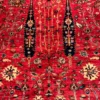 Close-up of vertical cypress tree motifs, flowering branches, and dense hand-spun wool pile on a red Afghan Bakhtiar rug.