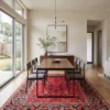 Hand-knotted Afghan Bakhtiar area rug styled beneath a long walnut dining table and eight grey chairs in an elegant dining room.