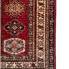 Detailed corner view of an Afghan Kazak wool runner rug showing an ivory geometric border, octagonal medallion, and neat white fringe.