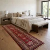 Hand-knotted Afghan Kazak wool runner rug laid beside a neutral upholstered bed in a serene, modern bedroom suite.
