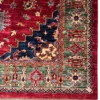 Detailed corner view of an Afghan Kazak wool rug showing the stepped navy spandrel, moss-green rosette border, zigzag guard stripe, and fringe edge.