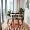 Hand-knotted Afghan Kilim wool rug centered beneath a round wood cafe dining table and two modern chairs in a sunlit breakfast nook.