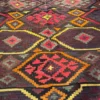 Close-up of interlocking stepped diamond medallions, tribal amulets, and textured flat-weave wool on an Afghan Kilim rug.