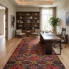 Large Afghan Kilim wool rug laid under a modern wood executive desk and office chair in a bright, high-ceilinged study.